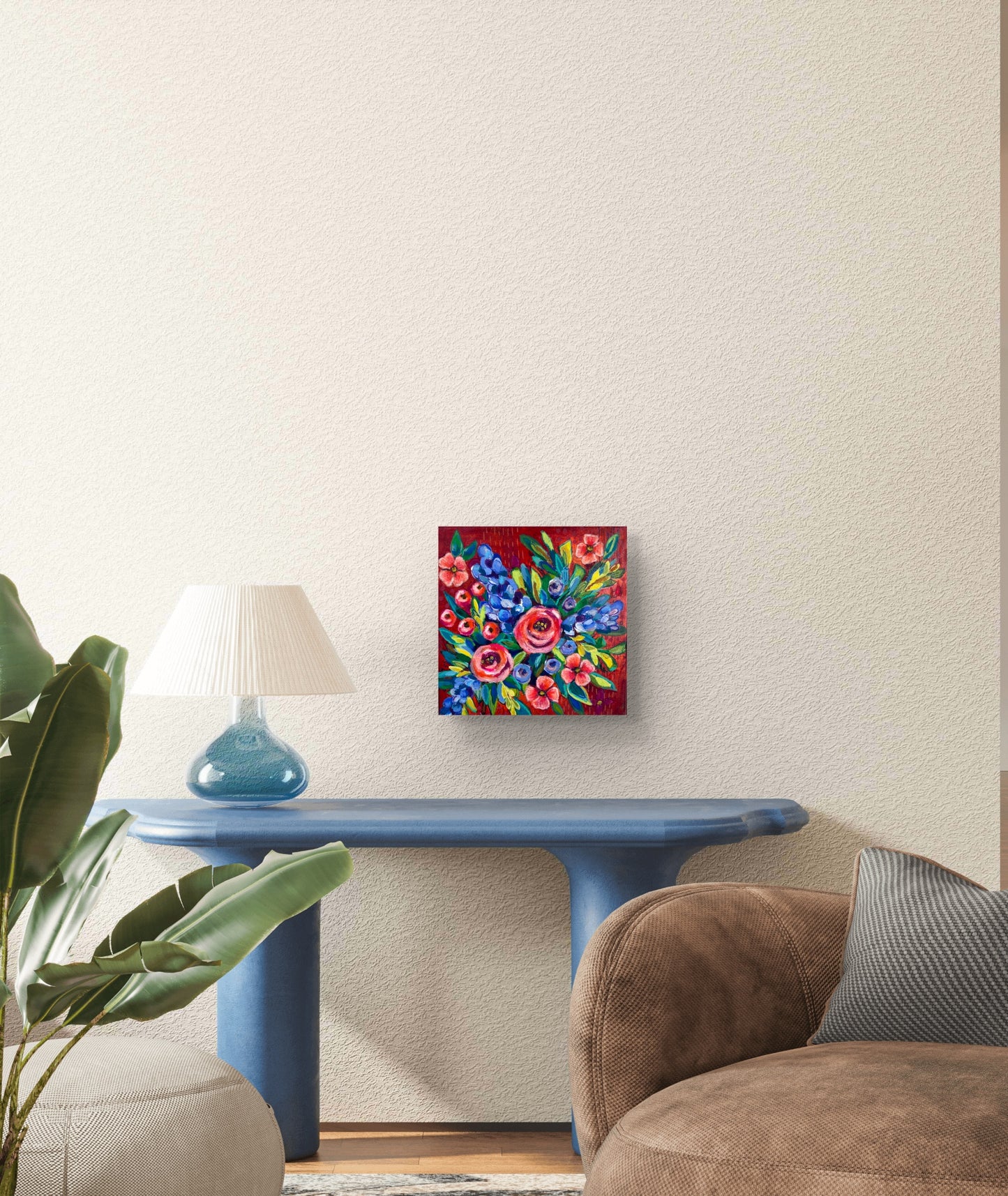 Colorful floral painting on a wall above a blue table in a living room.