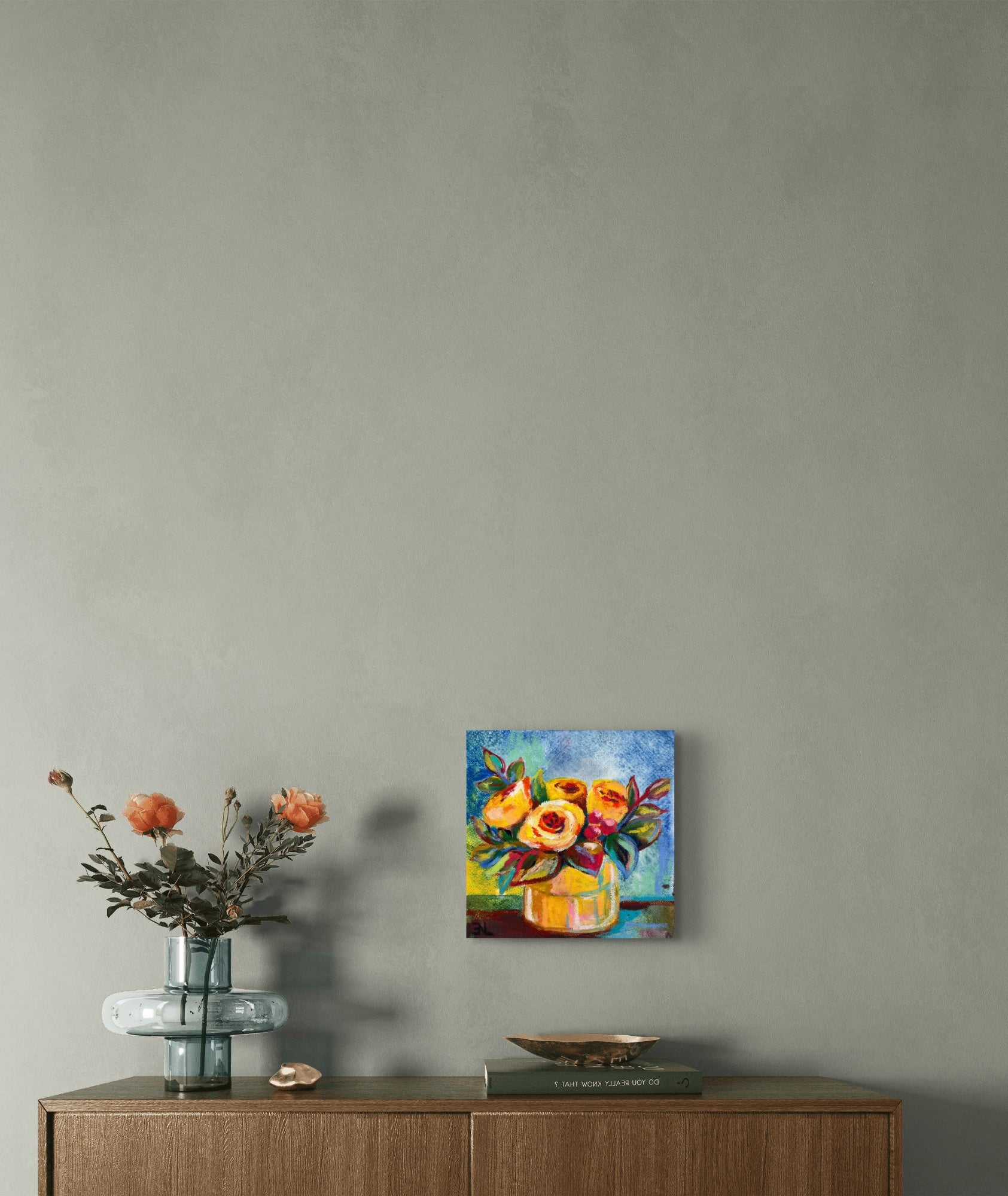 Small floral painting on a wall above a wooden cabinet with decorative items.