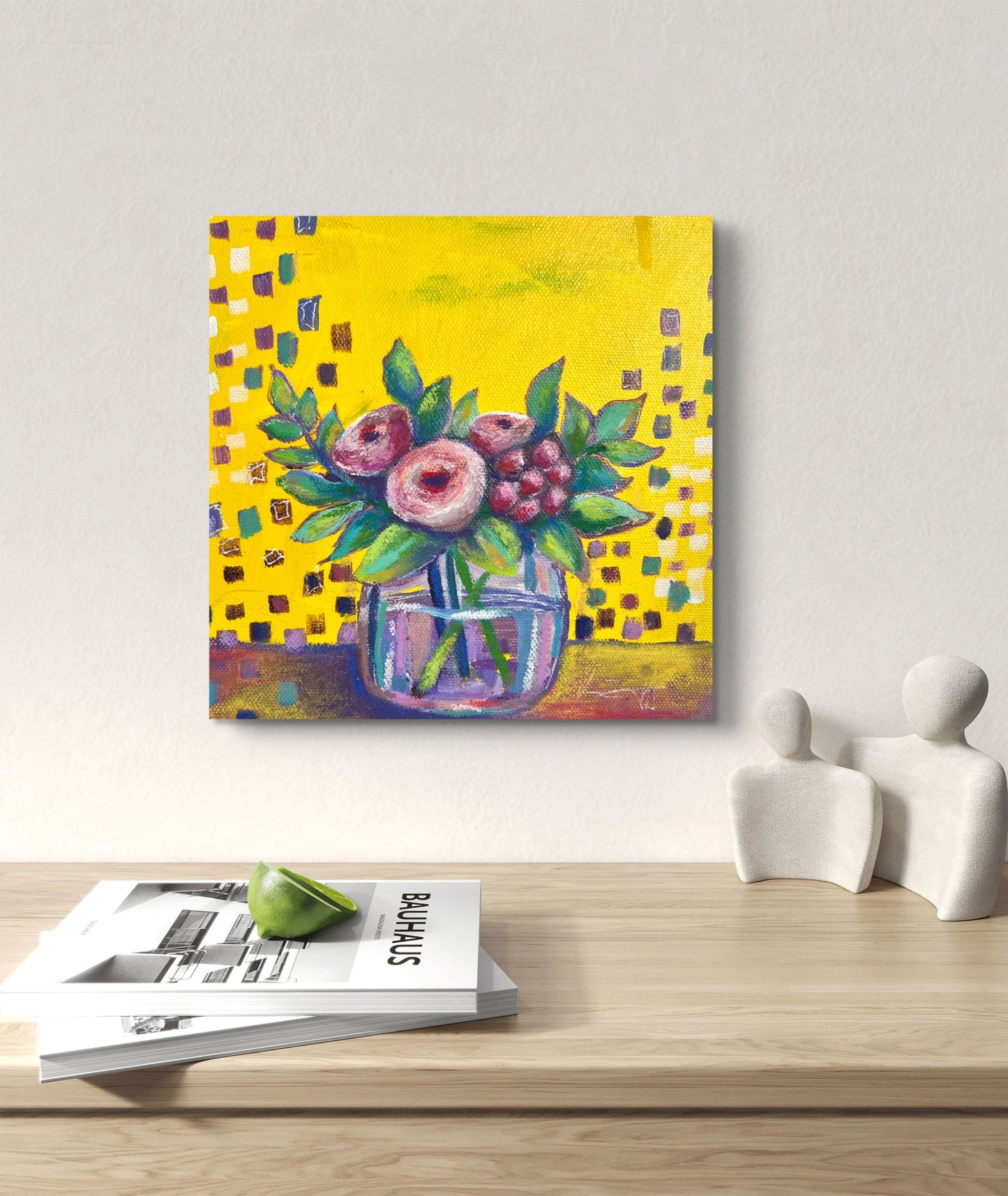 Colorful floral painting on a wall above a wooden table with magazines and decorative items.