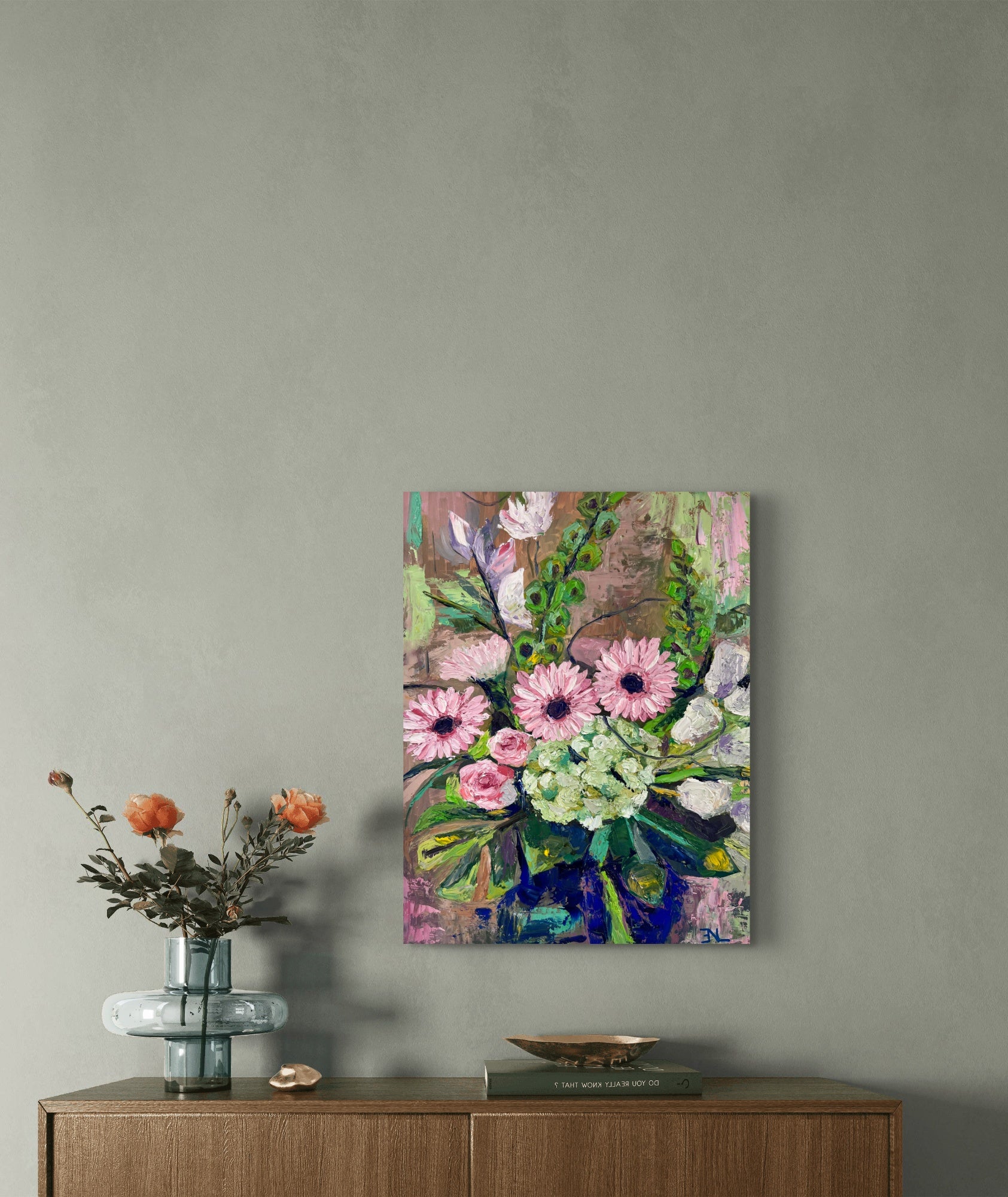 Floral painting on a wall above a wooden cabinet with a vase of flowers.