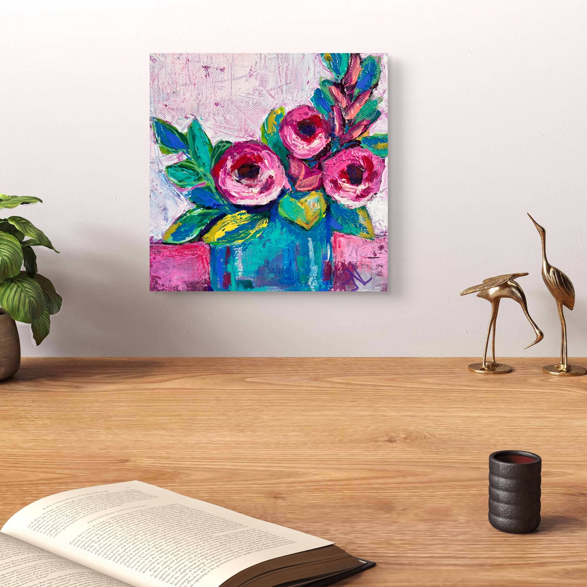Colorful floral painting on a wall above a wooden surface with decor items.