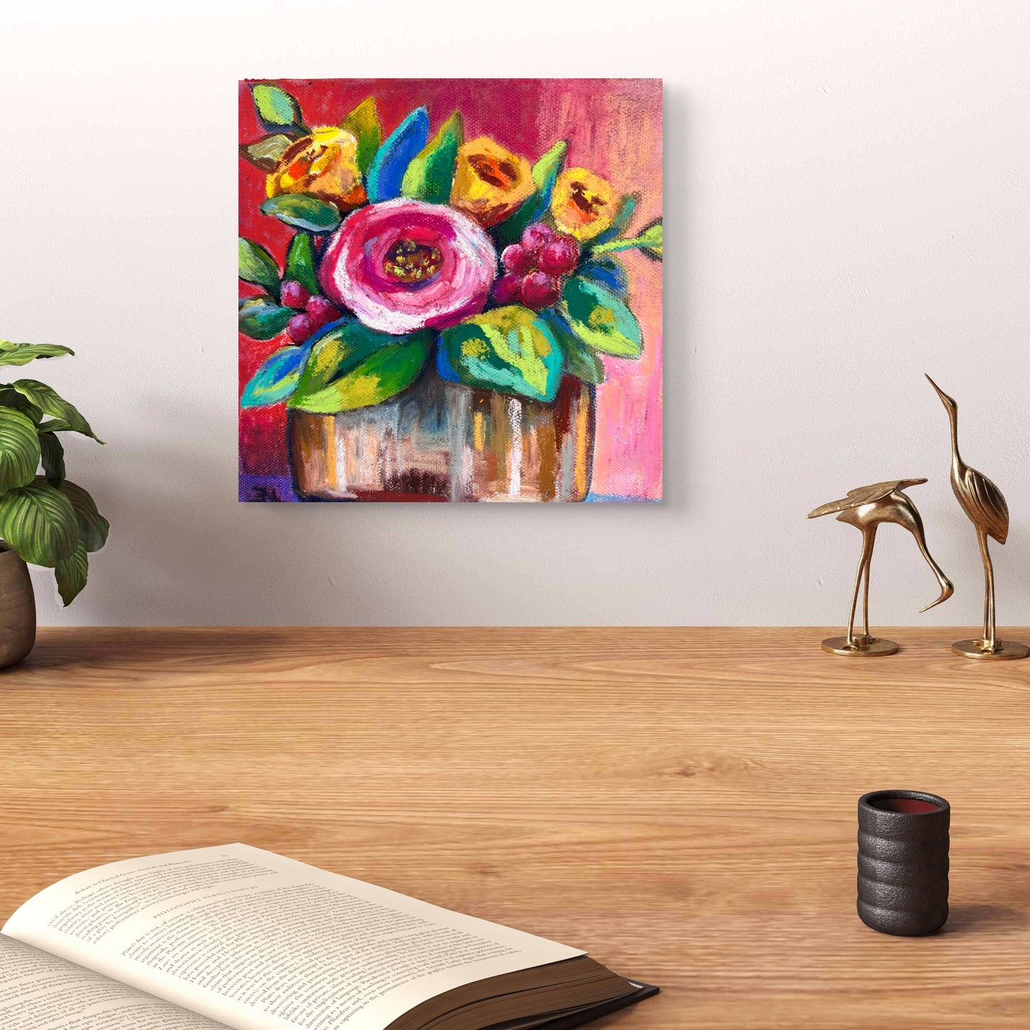 Colorful floral painting on a wall above a wooden surface with decor items.
